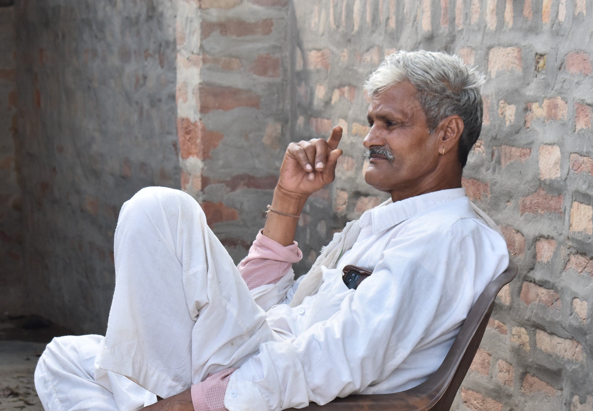 Man sitting on a chair against a brick wall